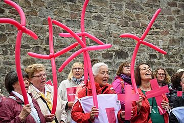 Frauen tragen purpurne Kreuze aus Luftballons bei einer Demonstration der kfd