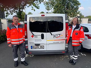 Gerhard Deißenböck und seine Kollegin stehen neben einem Bus des Bayerischen Roten Kreuz
