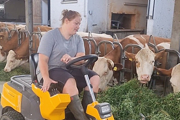 Frau auf Traktor füttert Kühe