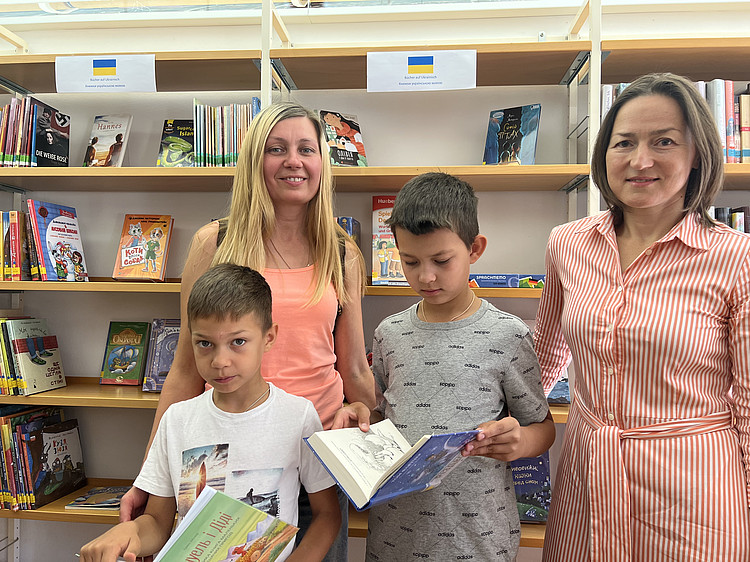 Nataliia Chychuk und ihre beiden Söhne mit Anna Demchenko, die das ukrainische Bücherangebot angestoßen hat. 