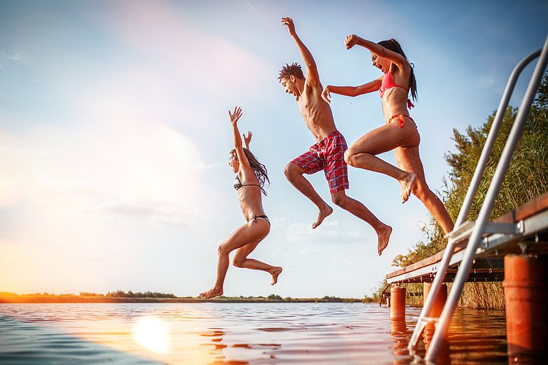 Drei junge Menschen springen ins Wasser