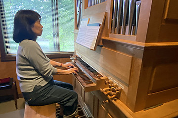 Eine Studentin spielt Orgel, vor ihr ein Notenblatt.