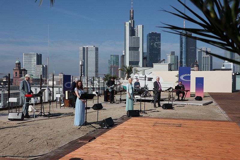 Menschen stehen auf Parkhausdach im Hintergrund die Frankfurter Skyline