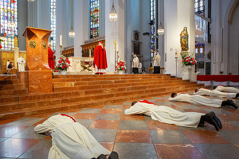 Männer liegen auf dem Bauch vor dem Altar, Kardinal Reinhard Marx steht mit dem Rücken zu ihnen