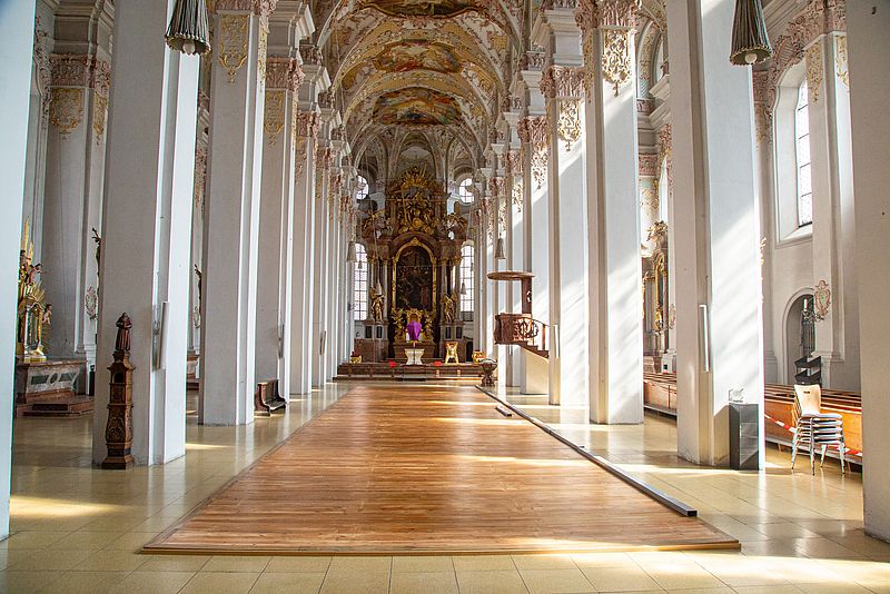 Innenraum mit renoviertem Holzpodest, ohne Kirchenbänke der Kirche Heilig Geist in München.
