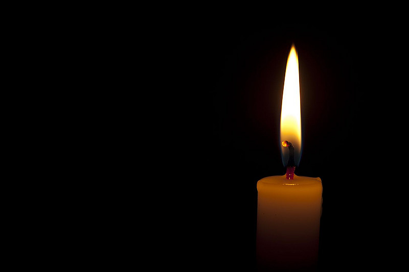 Brennende Kerze vor dunklem Hintergrund