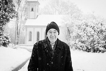 Portrait von Herrn Klinger im Schnee mit der Kirche im Hintergrund.
