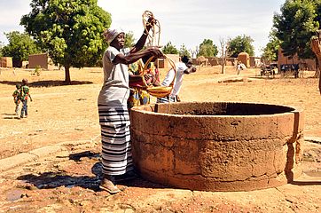 Frau holt Wasser aus einem Brunnen in Burkina Faso.