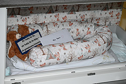 Die Babyklappe in Rosenheim, darin ein Babybett, ein Brief mit der Aufschrift "Für Mama", zwei Teddys und dem Schild "Ein Teddy für Sie, ein Teddy für Ihr Baby - als gemeinsame Erinnerung"