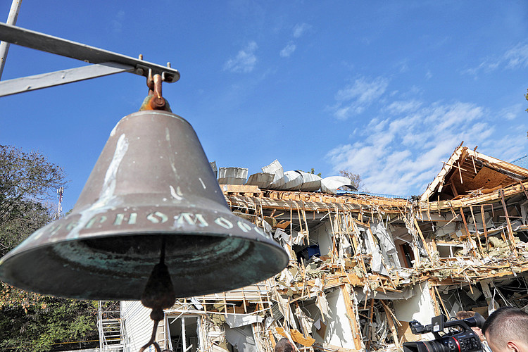 Glocke vor zerstörtem Gebäude in Ukraine