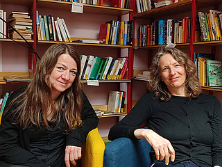 Zwei Frauen vor Bücherregal