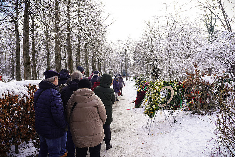 Menschen stehen im Schnee vor Grab
