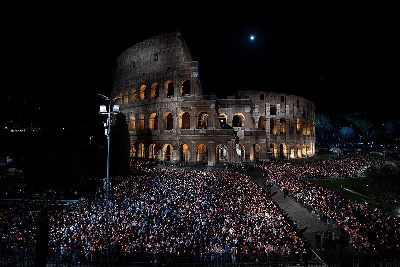 Menschenmenge an Gläubigen in der Nacht vor dem mit wenigen Lichtern angestrahlten Kolosseum
