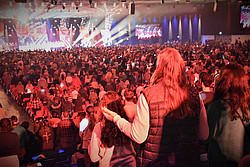 Menschen in Halle, Bühne mit bunten Lichtern