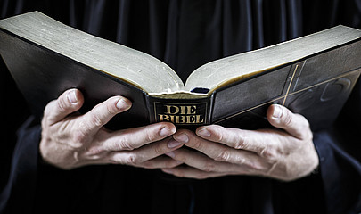 Hände halten aufgeschlagene Bibel