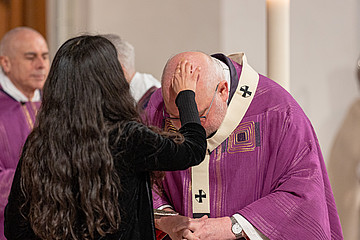 Ilaria Igliani zeichnet Kardinal Marx Aschekreuz auf die Stirn