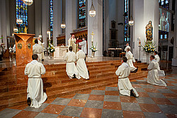 Diakonkandidaten knien vor dem Altar der Münchner Liebfrauenkirche