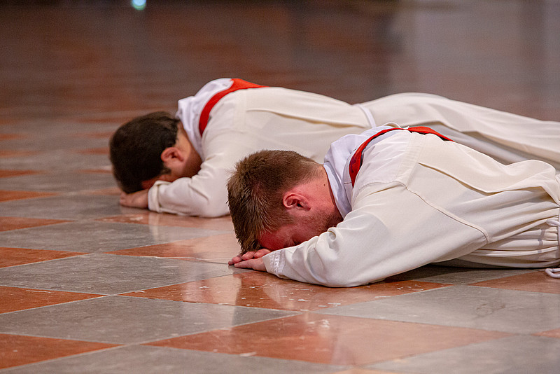 Zwei Neupriester liegen bei Priesterweihe mit dem Gesicht nach unten auf dem Boden