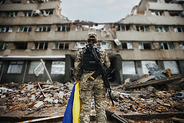 Ukrainische Soldatin vor einem zerstörten Gebäude