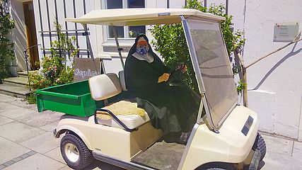 Nonne mit Maske im Golfkart