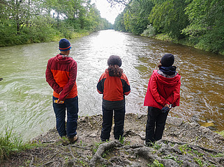 Drei der Initiatoren stehen nebeneinander vor einer Flußlandschaft.