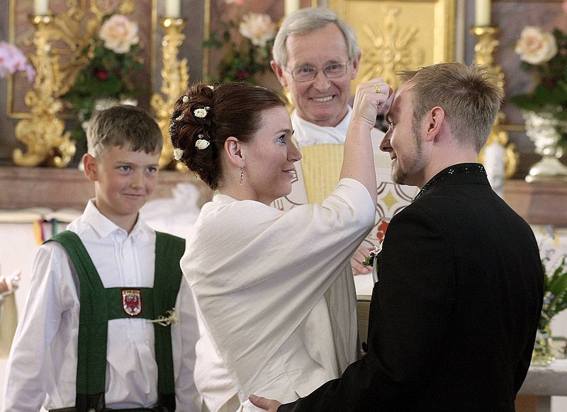 Ein Brautpaar segnet sich gegenseitig mit einem Kreuzzeichen auf die Stirn.