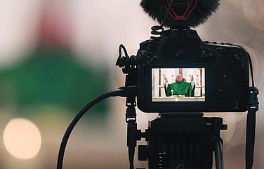 Kamera zeigt Aufnahme eines Priesters