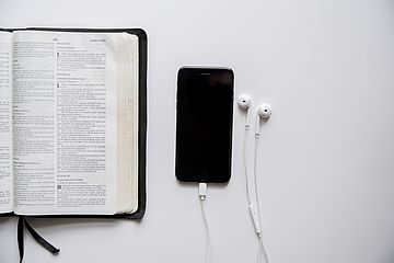 Bibel und ein Smartphone mit Kopfhörern