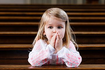 Mädchen betet in Kirchenbank