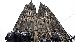 Polizisten stehen in Uniform vor dem Kölner Dom.