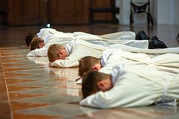 Diakone liegen bei der Weihe auf dem Boden vor dem Altar im Münchner Dom