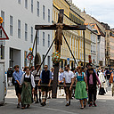 Ein großes Kruzifix wird von Menschen durch die Innenstadt getragen.