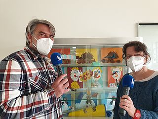 Zwei Personen mit Mundschutz im Interview