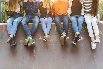 Beine von Jugendlichen, die auf einer Mauer sitzen