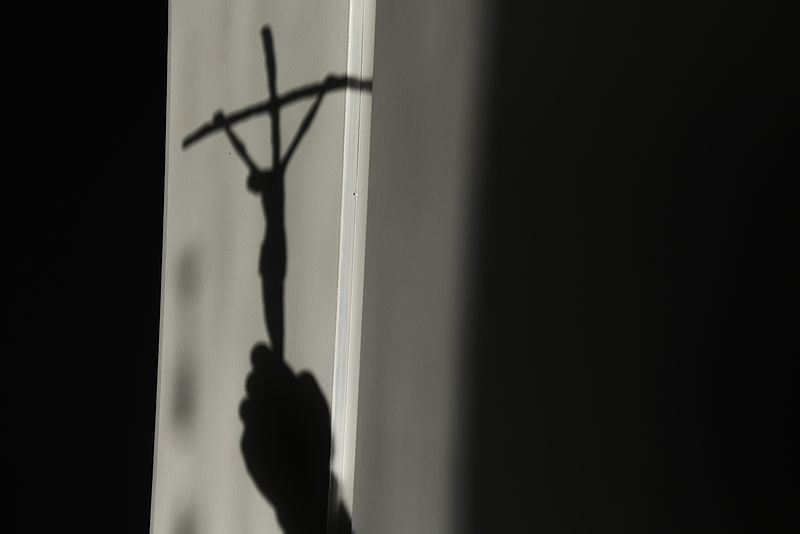Schatten eines Kruzifixes auf einer Wand.