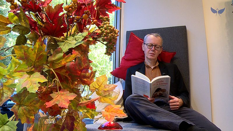 Alois Bierl liest Buch auf Fensterbank