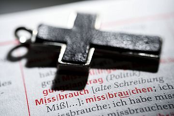 Kreuz liegt auf Wörterbuch, mit aufgeschlagener Seite zum Eintrag 