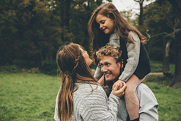 Vater mit Tochter auf Schultern und Mutter im Grünen