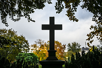Großes Kreuz auf einem Grabstein, der sich auf einem Friedhof befindet.