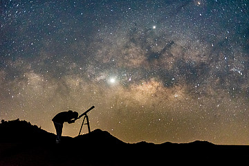 Person schaut durch Teleskop in den Sternenhimmel