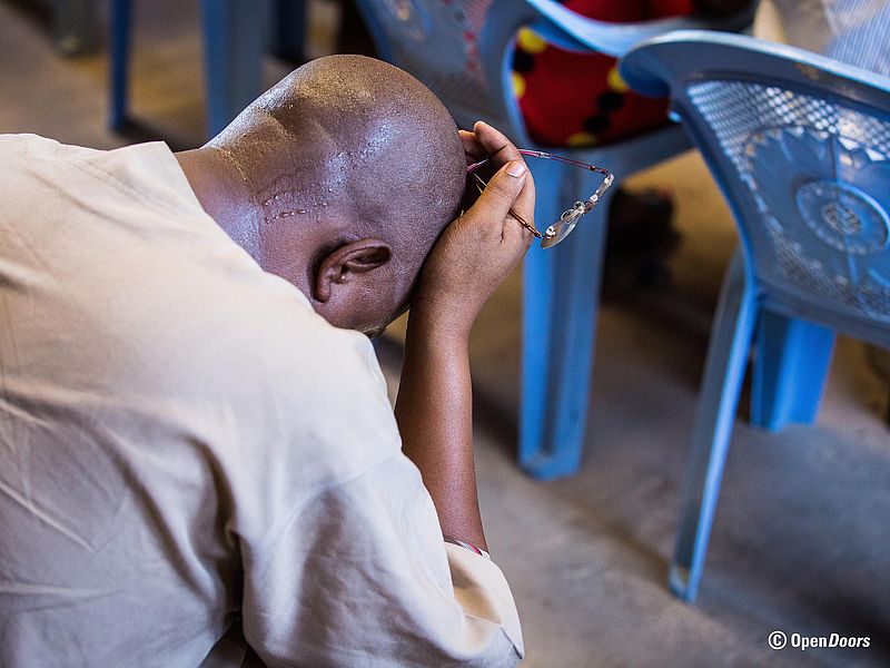 Ein Mann mit dunkler Hautfarbe kniet nieder und betet.