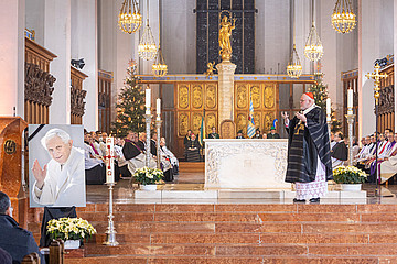 Kardinal Marx im Münchner Dom predigt neben ihm ein Bild des verstorbenen Benedikt XVI