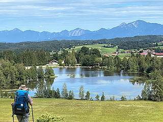 Person schaut in Landschaft mit See und Bergen