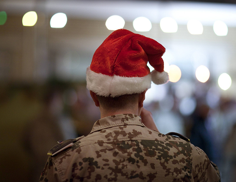 Mann in Camouflage von hinten, trägt eine Weihnachtsmütze