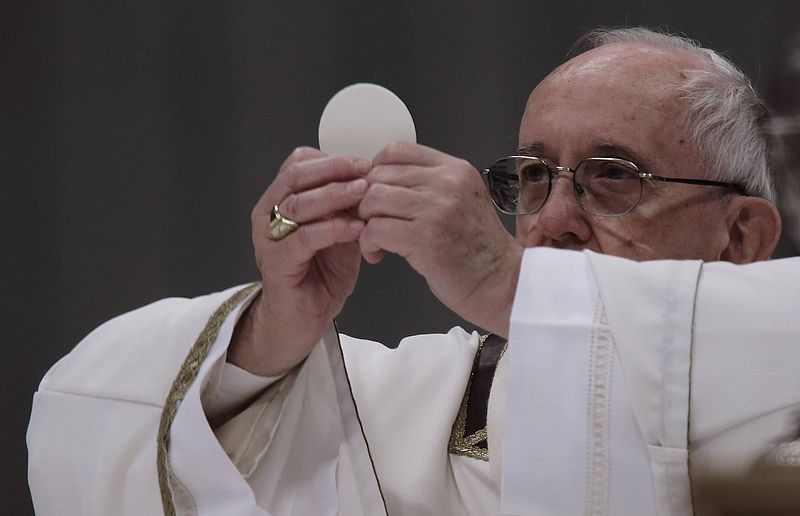 Papst Franziskus hält Hostie hoch.