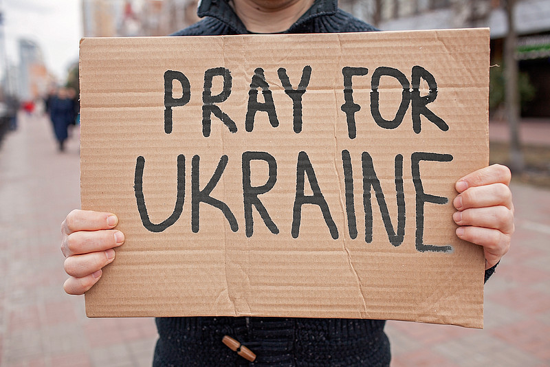 Pappschild mit der Aufschrift: "Pray for Ukraine"