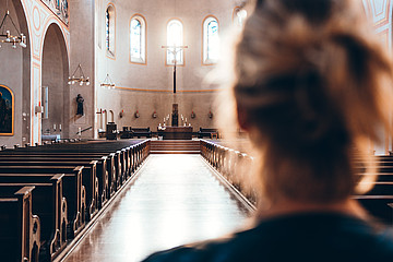 Frau in einer Kirche blickt Richtung Altar