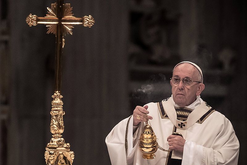 Papst Franziskus schwenkt ein Weihrauchfass, links daneben ist ein Kreuz