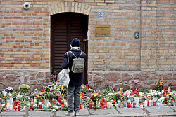Eine Frau steht nach dem Anschlag vor der Synagoge in Halle und betrachtet die Kerzen und Blumen.