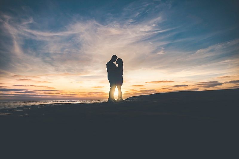 Siluette eines sich zugewandten Paares vor einem Sonnenuntergang.